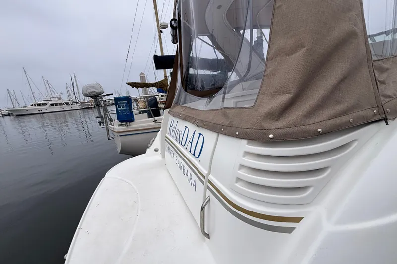 2004 Larson 310 boat docked in a marina, featuring a beige canopy and calm waters.
