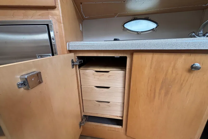 2004 Larson 310 boat interior with open wooden cabinet and drawers.