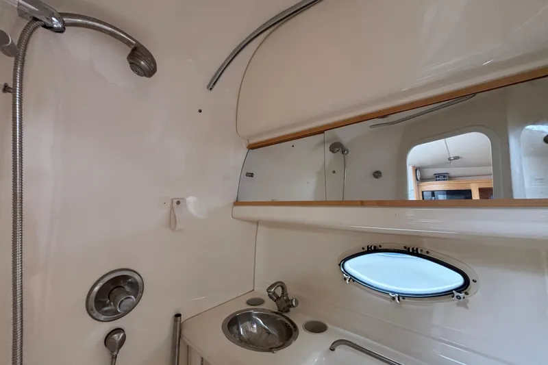 Bathroom interior of a 2004 Larson 310 boat with sink, mirror, and porthole window.