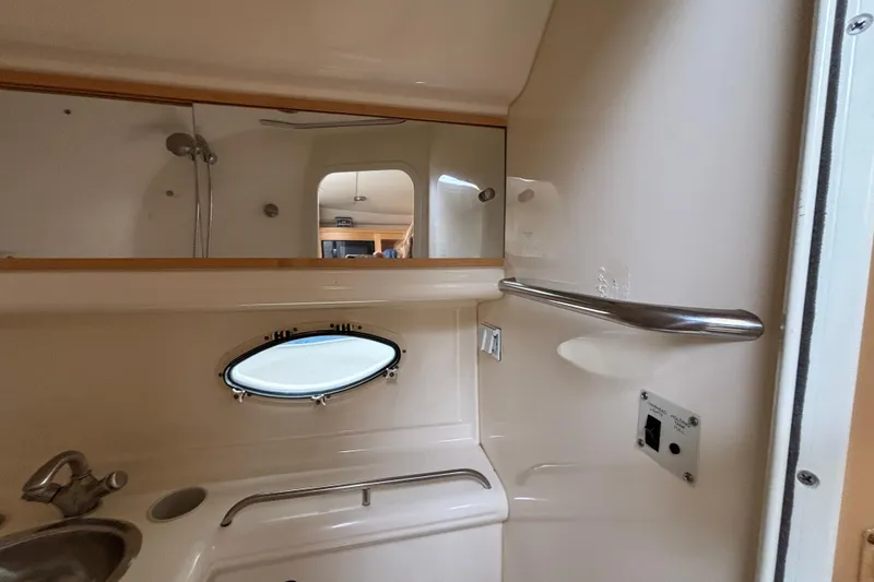 2004 Larson 310 boat bathroom interior with sink, mirror, and porthole window.
