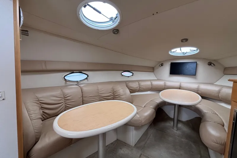 Luxurious interior of 2004 Larson 310 boat with leather seating and round tables.