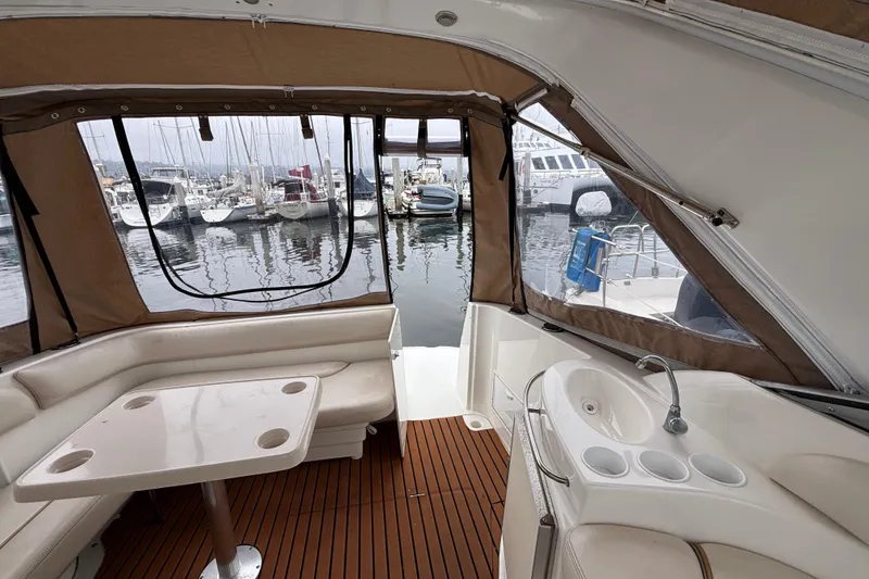 Interior of a 2004 Larson 310 boat with seating, table, and marina view.