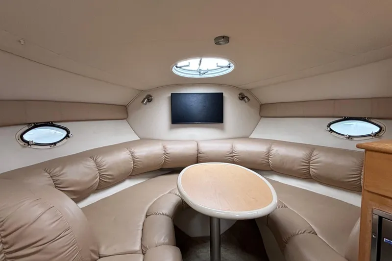 Interior of a 2004 Larson 310 boat with beige seating and a round table.