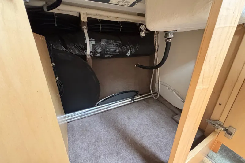 Interior storage compartment of a 2004 Larson 310 boat, showing pipes and insulation.