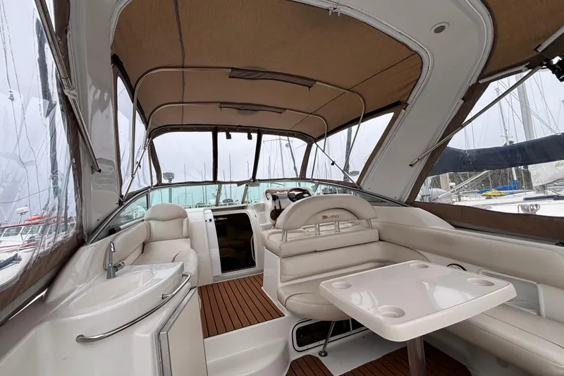Interior of a 2004 Larson 310 boat with seating and table under a canopy.