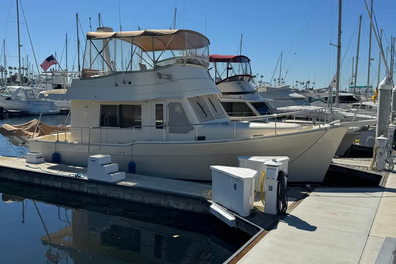 2006 Mainship 34 Trawler docked at marina under clear blue sky.