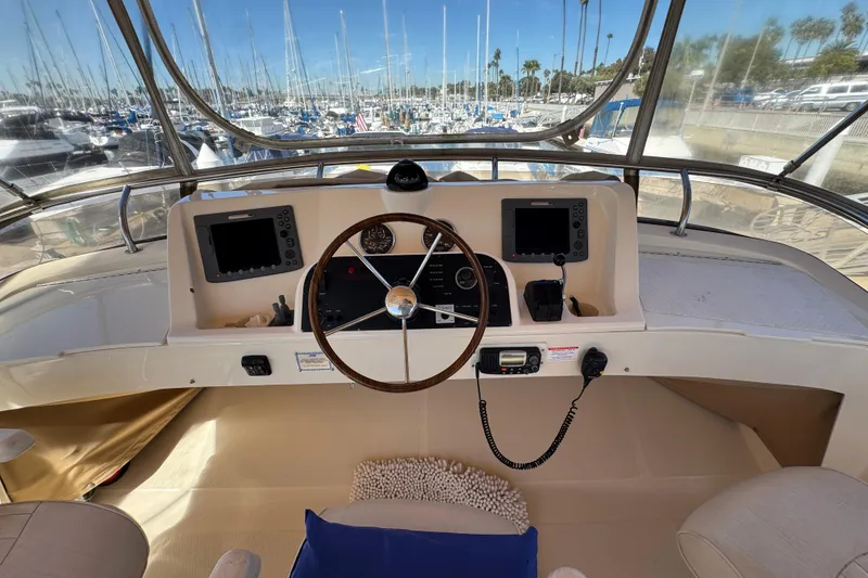 2006 Mainship 34 Trawler helm with steering wheel, navigation equipment, and marina view.