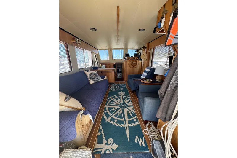 Interior of 2006 Mainship 34 Trawler with nautical decor and cozy seating.