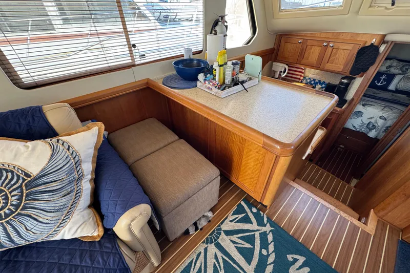 Interior of 2006 Mainship 34 Trawler with cozy seating and wooden cabinetry.