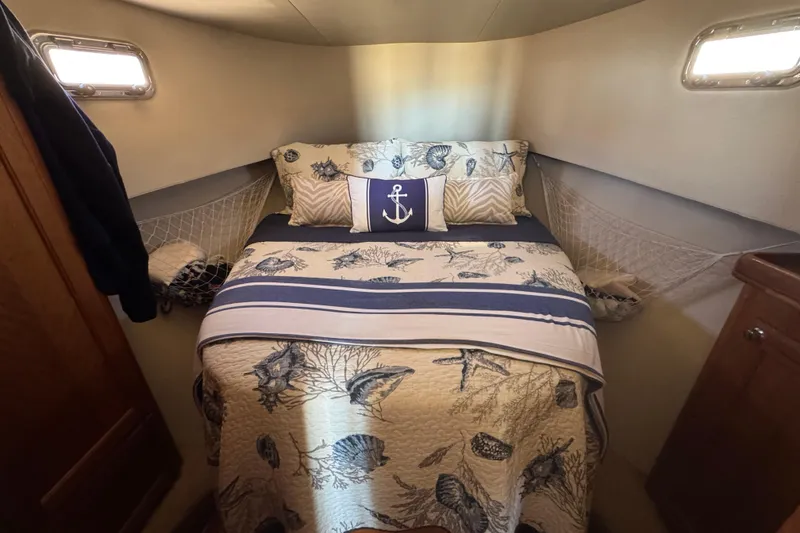 Cozy cabin bedroom in 2006 Mainship 34 Trawler with nautical-themed bedding.