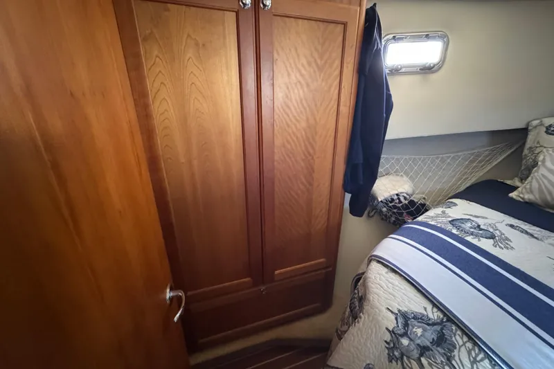 Cozy cabin interior of 2006 Mainship 34 Trawler with wooden closet and nautical bedding.