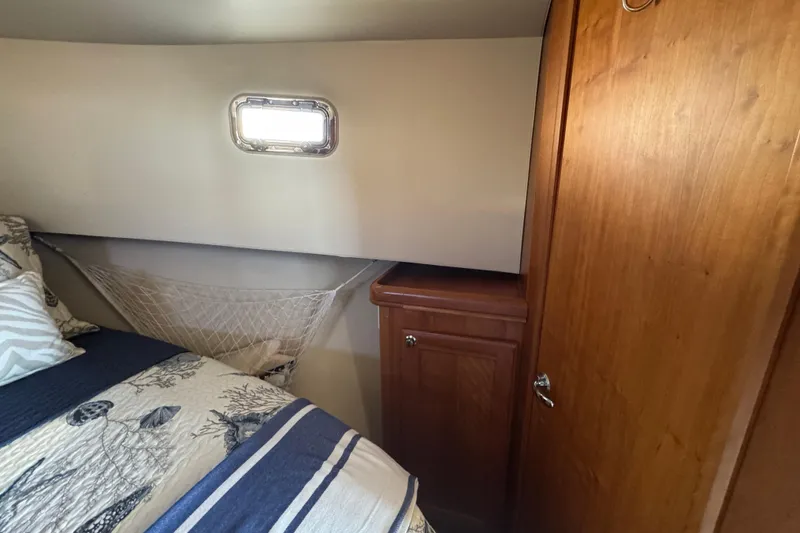 Cozy cabin interior of 2006 Mainship 34 Trawler with wooden cabinetry and nautical decor.