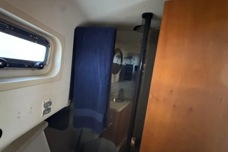 Bathroom interior of 2006 Mainship 34 Trawler with wooden door and porthole window.