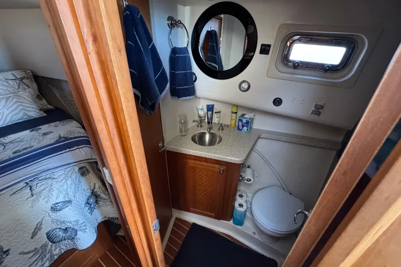 Bathroom interior of 2006 Mainship 34 Trawler with sink, mirror, and nautical decor.