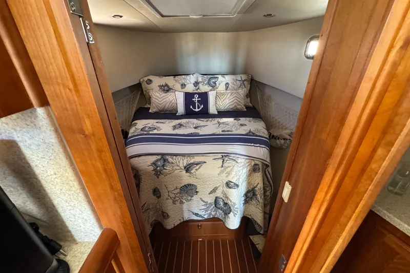 Cozy cabin interior of 2006 Mainship 34 Trawler with nautical-themed bedding.