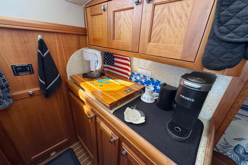 Cozy galley in 2006 Mainship 34 Trawler with wooden cabinets and coffee maker.