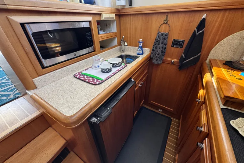 2006 Mainship 34 Trawler galley with microwave, sink, and wooden cabinetry.