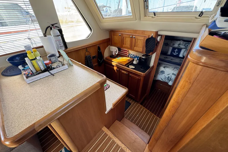 Cozy interior of 2006 Mainship 34 Trawler with kitchenette and nautical-themed decor.