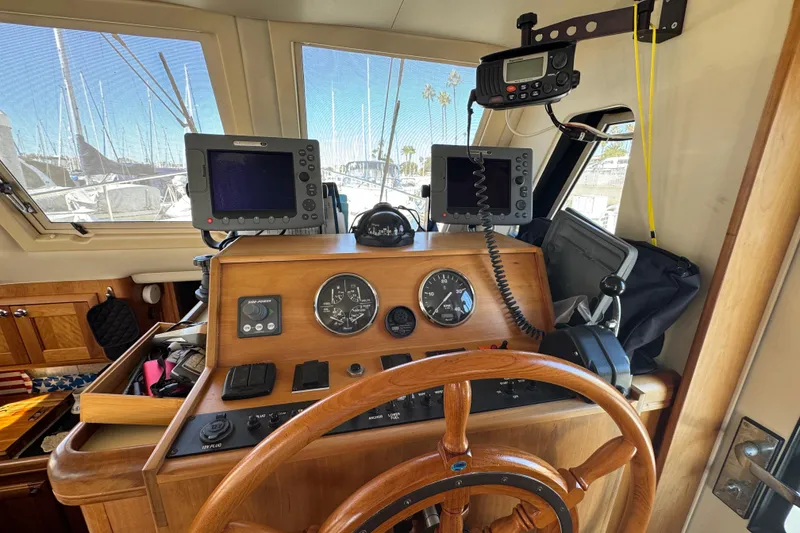 2006 Mainship 34 Trawler helm with navigation equipment and wooden steering wheel.