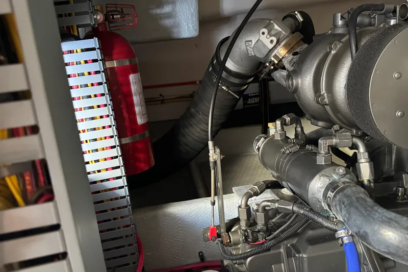Engine room of 2006 Mainship 34 Trawler with fire extinguisher and mechanical components.