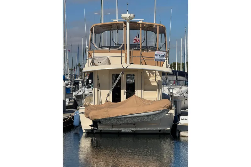 2006 Mainship 34 Trawler docked, featuring covered dinghy and "For Sale" sign.