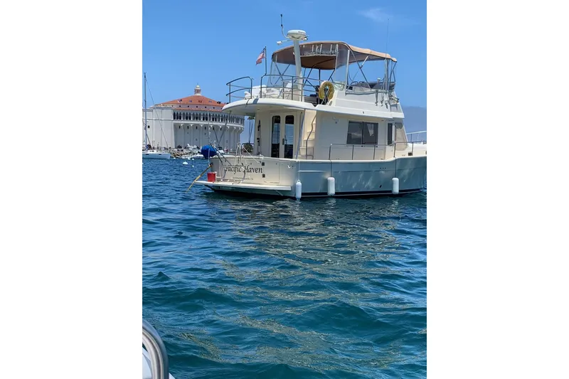 2006 Mainship 34 Trawler on water near a historic building.