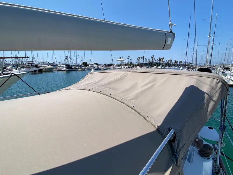 2003 Beneteau 423 sailboat docked in a marina with a beige canopy.