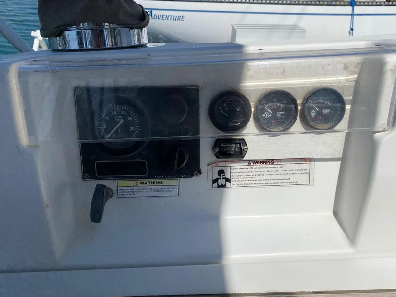 Control panel of a 2003 Beneteau 423 sailboat with gauges and warning labels.