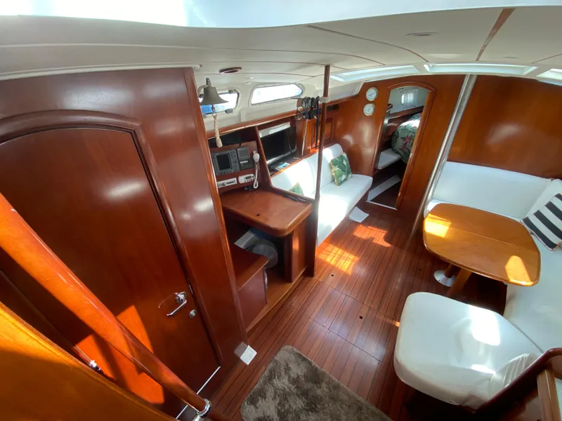 Interior of 2003 Beneteau 423 sailboat with wood finish and cozy seating area.