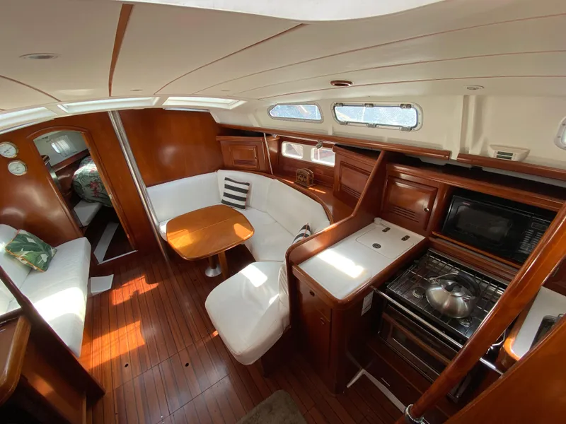 Interior of 2003 Beneteau 423 sailboat with wood finish, dining area, and kitchen.