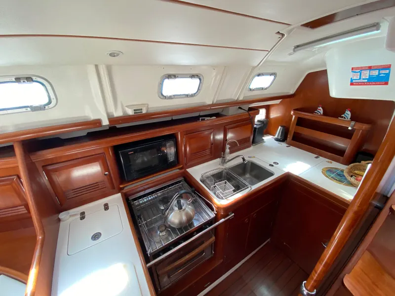 Interior of 2003 Beneteau 423 yacht kitchen with wood cabinetry and modern appliances.