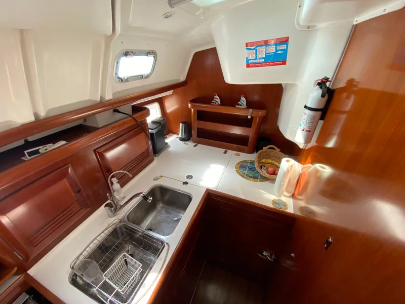 Galley kitchen in 2003 Beneteau 423 sailboat with wooden cabinetry and stainless steel sink.