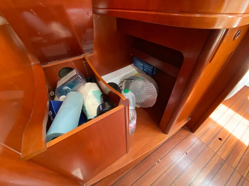 Storage compartments inside a 2003 Beneteau 423 yacht, featuring wooden cabinetry and various items.