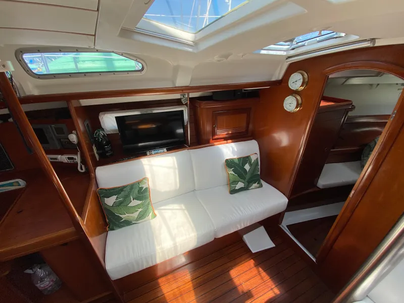 Interior of 2003 Beneteau 423 yacht with white seating, wooden finish, and decorative pillows.