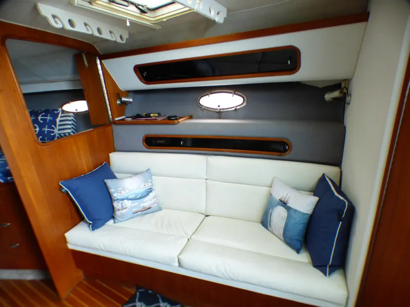 1989 Tiara Yachts 3300 interior with white sofa, nautical pillows, and wooden accents.