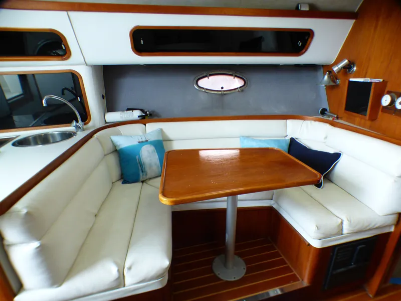 1989 Tiara Yachts 3300 interior with white seating, wooden table, and nautical decor.