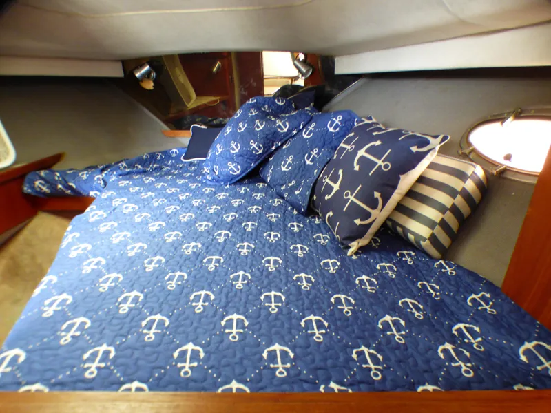 1989 Tiara Yachts 3300 cabin with nautical-themed bedding and anchor-patterned decor.