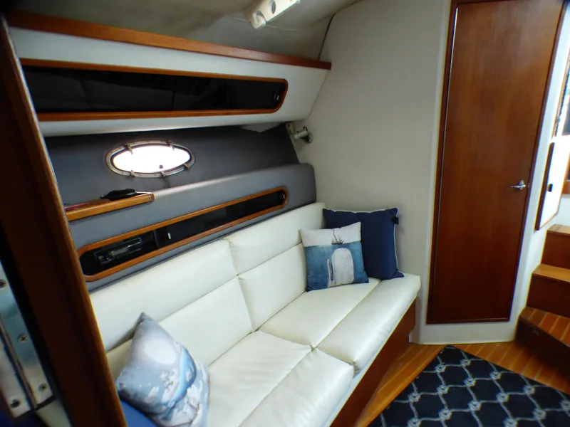 1989 Tiara Yachts 3300 interior with white leather seating and nautical-themed pillows.