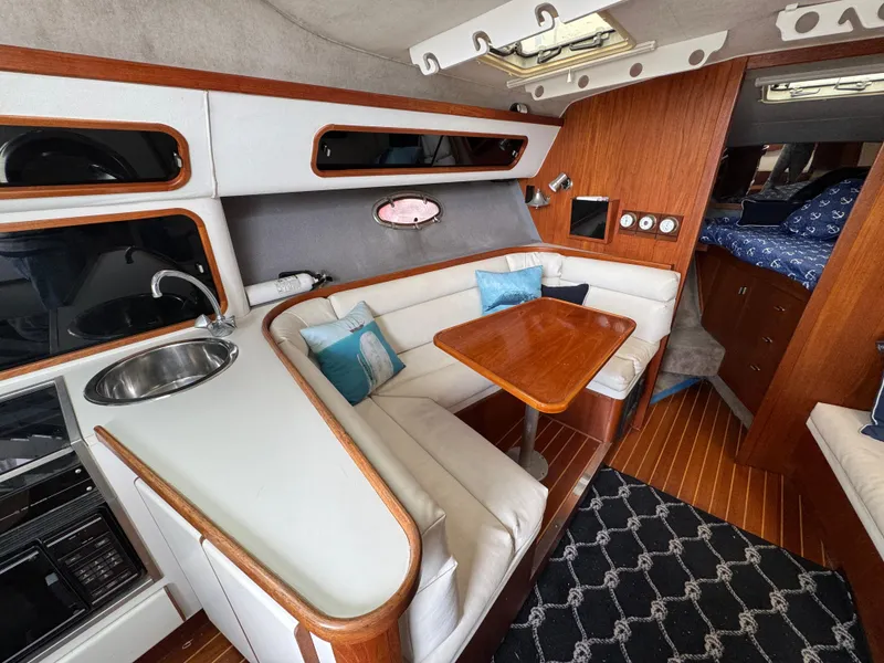 1989 Tiara Yachts 3300 interior with cozy seating, wooden table, and modern amenities.