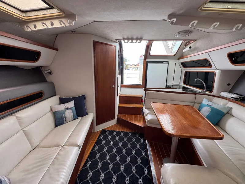 1989 Tiara Yachts 3300 interior with white seating, wooden table, and nautical decor.