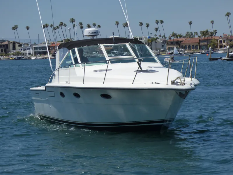 1989 Tiara Yachts 3300 cruising on a sunny day near a coastal marina.