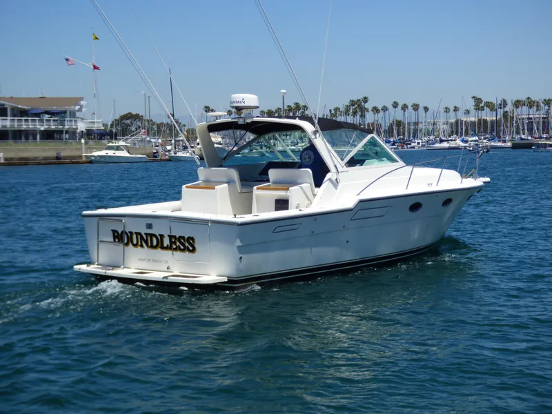1989 Tiara Yachts 3300 cruising in a marina, clear skies, palm trees in background.