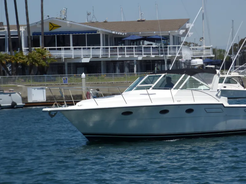 1989 Tiara Yachts 3300 cruising near a marina with a clubhouse in the background.