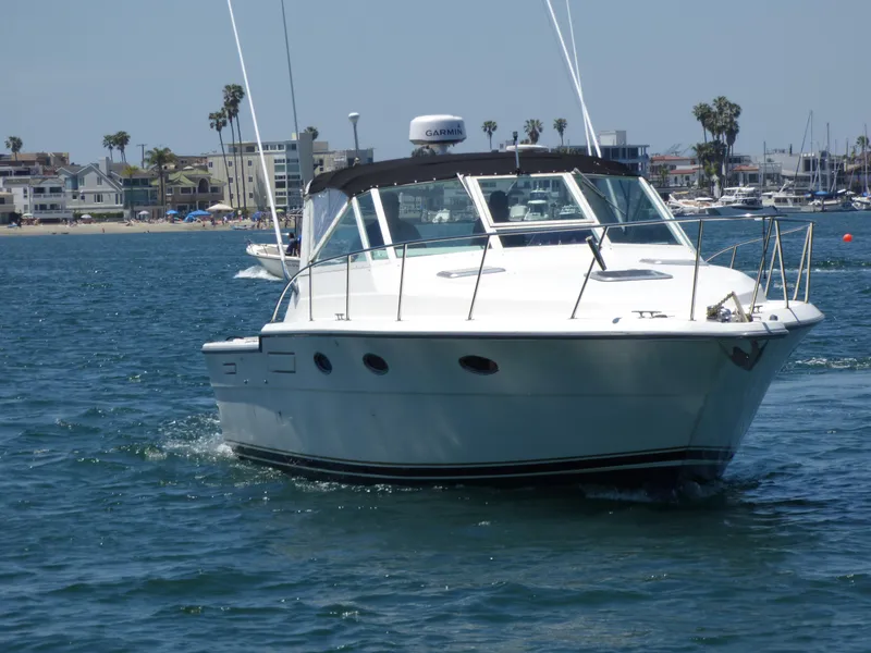 1989 Tiara Yachts 3300 cruising on a sunny day near a coastal city.