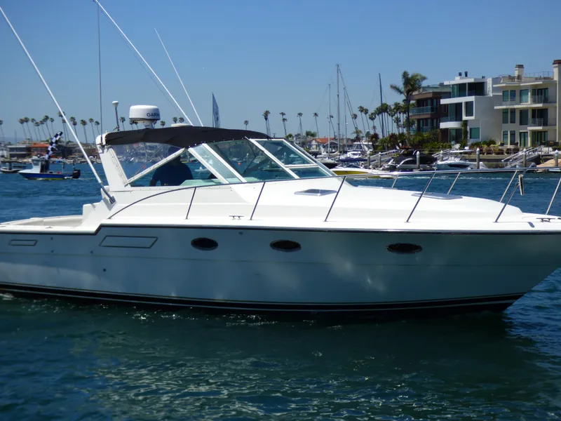 1989 Tiara Yachts 3300 cruising in a marina with modern waterfront homes.