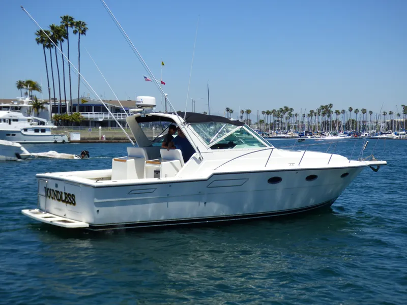 1989 Tiara Yachts 3300 cruising in a sunny marina with palm trees.