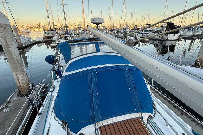 Hunter 31 sailboat, 2007 model, docked in a marina with blue canopy and wooden deck.