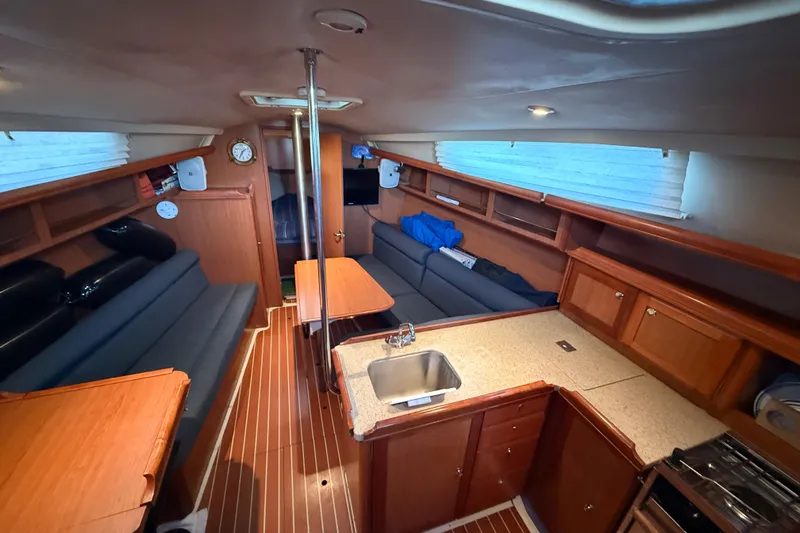Interior of 2007 Hunter 31 sailboat with cozy seating, kitchen, and wooden cabinetry.