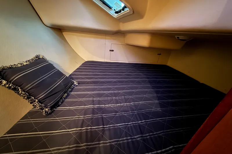Cozy cabin interior of 2007 Hunter 31 sailboat with striped bedding and pillow.