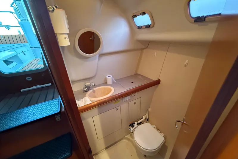 Compact bathroom in 2007 Hunter 31 sailboat with sink, toilet, and portholes.